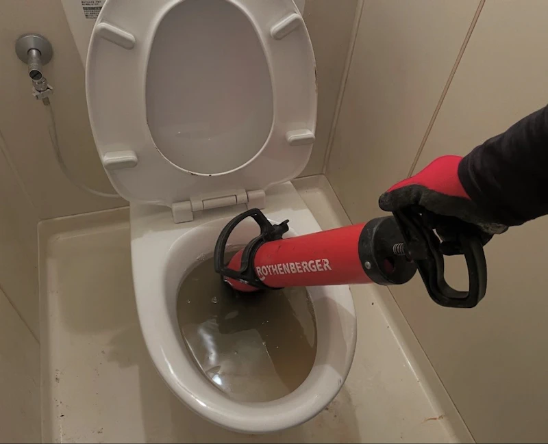 専用の器具でトイレのつまりを除去しているAir Riseの作業写真